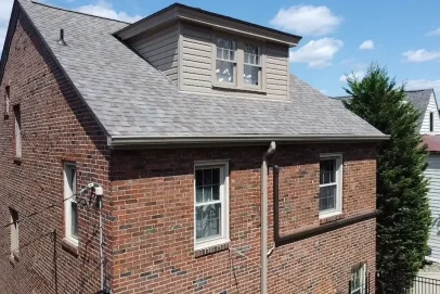 Red brick house with dormer, blue sky.